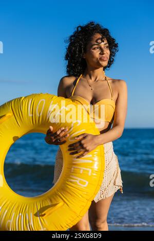 Lateinische Frau mit aufblasbarem Ring am Strand, der Sommerurlaub genießt Stockfoto