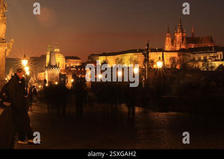 Mann, der bei Nacht auf der beleuchteten Karlsbrücke im Zentrum von Prag steht, mit Blick auf die Prager Burg Stockfoto