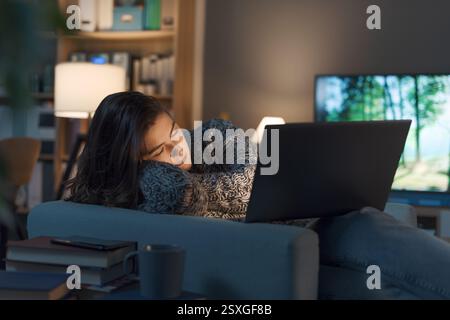 Müde entspannte Frau, die zu Hause auf dem Sessel schlief, schlief ein, während sie Filme auf ihrem Laptop ansah Stockfoto