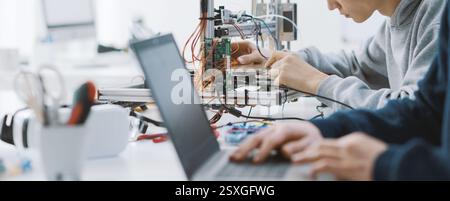 Studenten, die im Labor an einem Projekt arbeiten, verwenden einen Laptop und einen 3D-Drucker Stockfoto
