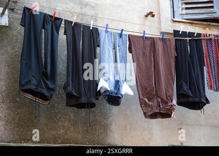 Es gibt verschiedene Kleidung, die an einer Wäscheleine vor einem Gebäude hängt Stockfoto