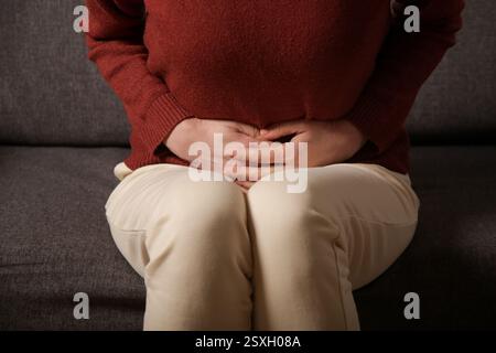 Magenschmerzen. Frau mit Magenverstimmung oder Menstruationskrämpfen. Eine junge Frau hat Bauchschmerzen in der Wohnung. Stockfoto