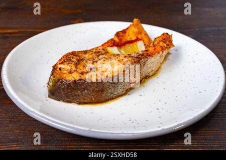 Ein perfekt gegrilltes Lachsfilet auf einem einfachen Teller, garniert mit frischen Zitronenscheiben und Kräutern. Das Gericht sieht herzhaft und appetitlich aus, ideal für Stockfoto