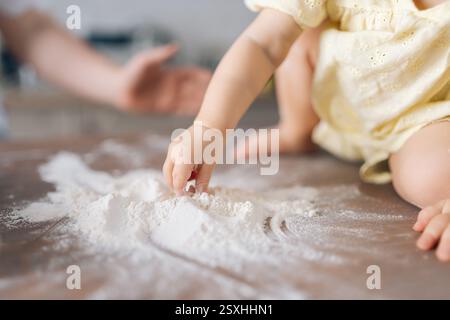 Nahaufnahme eines unwiedererkennbaren, neugierigen Mädchens, das auf spielerische Weise Mehl streut und fröhliche Momente der Kindheitserkundung festhält Stockfoto