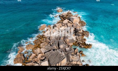 Granitfelsen, umgeben von türkisfarbenem Wasser, mit zerklüfteten Strukturen und Mustern. La Digue, Seychellen. Stockfoto