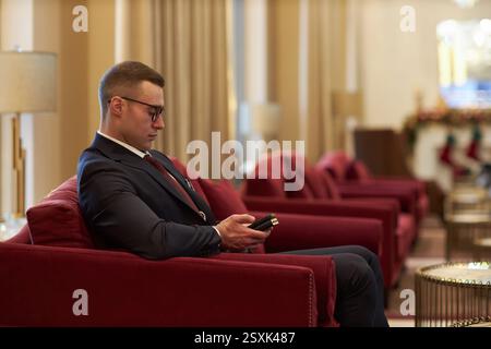 Mann im Business-Anzug, der in der Lobby des Luxushotels sitzt Stockfoto