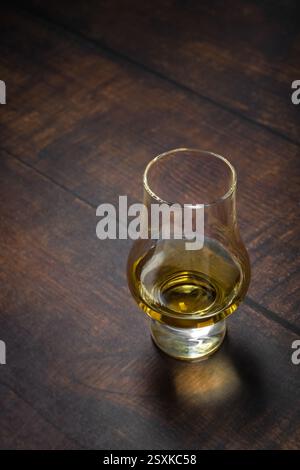 Nahaufnahme von Single Malt Whiskey oder Scotch Whisky Verkostungsglas auf dunklem Holztisch Stockfoto