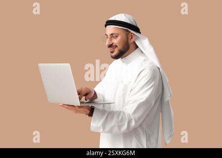 Arabischer Geschäftsmann, der mit Laptop auf beigefarbenem Hintergrund arbeitet Stockfoto