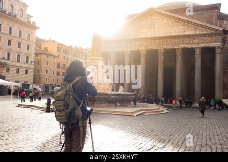 Rom, Italien - 8. Januar 2025: Touristen-Backpacker-Fotograf mit Kamera vor dem pantheon-Tempel und Obelisk im warmen Morgenlicht, um die Sehenswürdigkeiten zu fotografieren Stockfoto