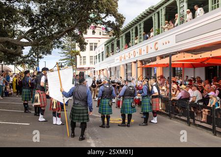 Eine Highland Pipe and Drum Band vor dem historischen Masonic Hotel, Napier, Neuseeland, während des jährlichen Art Deco Festivals Stockfoto