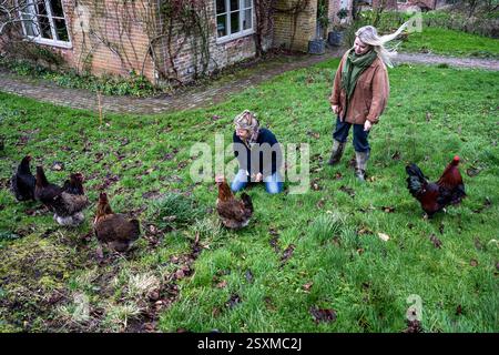 Mattie und Rose Howard mit Hühnern im Garten des East Sussex Tudor Farmhouse, England, Großbritannien. Stockfoto