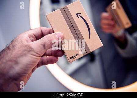 Paris, Frankreich - 22. November 2022: Eine Person hält ein kleines Papppaket mit Amazon-Markenzeichen vor einem Spiegel, das das Bild der Box symbolilizi widerspiegelt Stockfoto