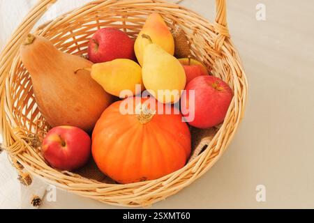 Äpfel, Birnen und Kürbisse in einem Strohkorb. Orange reife Früchte. Obst ist eine beliebte Zutat beim Kochen. Draufsicht. Platz für Text. Stockfoto