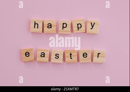 Blöcke mit den Worten Happy Easter auf rosafarbenem Hintergrund, perfekt für festliche Grüße Stockfoto