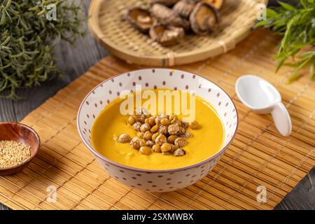 Cremige Kürbissuppe garniert mit gerösteten Kichererbsen in Schüssel auf chinesischem Restauranttisch Stockfoto