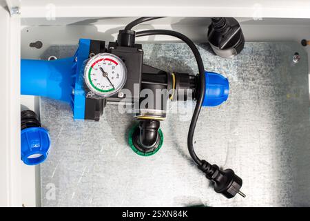 Automatischer Wasserversorgungsregler mit Manometer in einem Metallkasten. Installation eines Tropfbewässerungssystems. Stockfoto