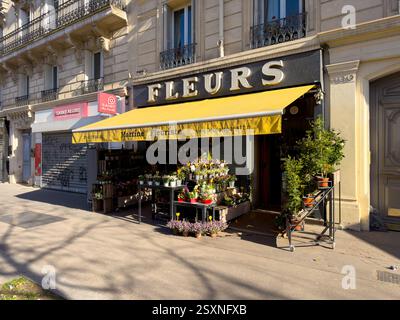 Das pulsierende Blumengeschäft in Paris zeigt die Blüten unter der sonnigen gelben Markise Stockfoto