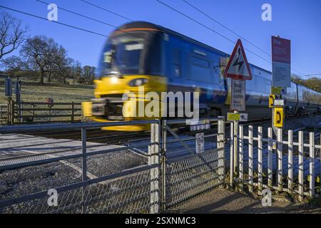 Northern Rail Zug fährt über unbemannte Bahnübergänge (streckenseitige Eisenbahnwarnungen) - Burley in Wharfedale, West Yorkshire, England, Großbritannien. Stockfoto
