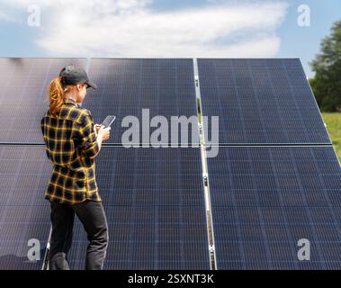 Weibliche Ingenieurin im Solarkraftwerk, die drahtlose Technologie zur Überwachung von Panels verwendet Stockfoto