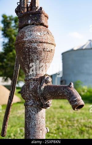 Dies ist eine Nahaufnahme einer alten rostigen antiken Handwasserpumpe in einer ländlichen Umgebung in Iowa, USA. Es erinnert an rustikalen Charme und historisches Ambiente. Stockfoto