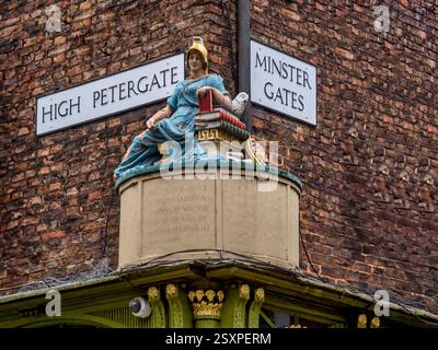 Dies ist die Statue von Minerva, der römischen Göttin der Weisheit, daher die Bücher des Lernens und die Weise Eule, die hoch oben auf der Mauer in York thront Stockfoto