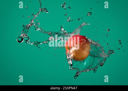 Stop Motion Wasserspritzer und roter Apfel auf smaragdgrünem Hintergrund. Stockfoto
