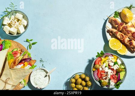 Griechische Essensauswahl. Huhn Gyros Wrap, Souvlaki, Pita, griechischer Salat, Tzatziki, Fetakäse, Oliven für gesundes Mittagessen auf blauem Hintergrund, Kopierraum Stockfoto