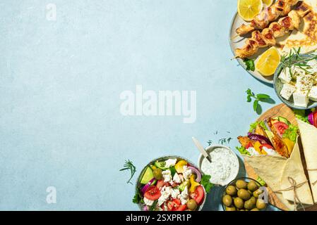 Griechische Essensauswahl. Huhn Gyros Wrap, Souvlaki, Pita, griechischer Salat, Tzatziki, Fetakäse, Oliven für gesundes Mittagessen auf blauem Hintergrund, Kopierraum Stockfoto