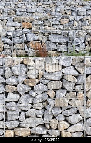 Abstrakter Hintergrund einer Gabionenwand aus Granitsteinen und Drahtgeflecht Stockfoto