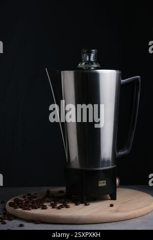Kaffeemaschine und Kaffeebohnen auf schwarzem Hintergrund, Studio-Aufnahme Stockfoto