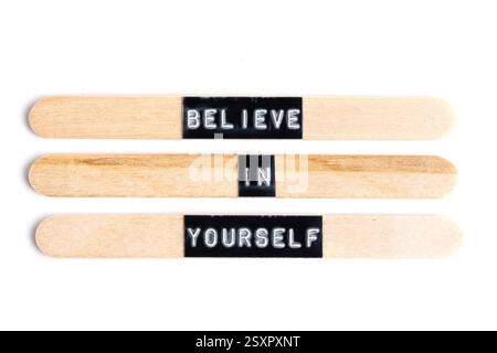 Glauben Sie an sich selbst Worte, die auf Holzstäben auf weißem Hintergrund geschrieben sind Stockfoto