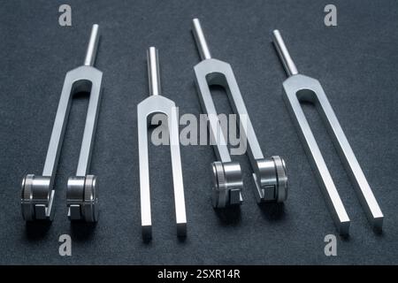 Satz gewichteter und ungewichteter Stimmgabeln aus Metall, die zum Abstimmen von Musikinstrumenten, zur Klangtherapie, zur Chakra-Heilung oder Entspannung verwendet werden. Stockfoto