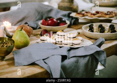 Schöner Desserttisch mit verschiedenen Gebäckstücken und frischem Obst in rustikaler Umgebung Stockfoto