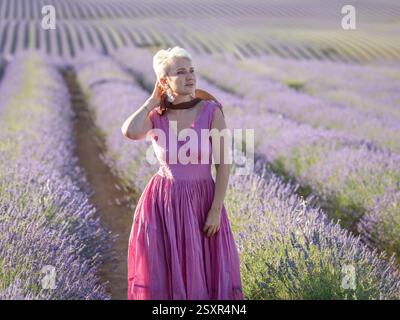 Wunderschönes kurzhaariges Mädchen steht in endlosen Feldern mit blühendem Lavendel Stockfoto