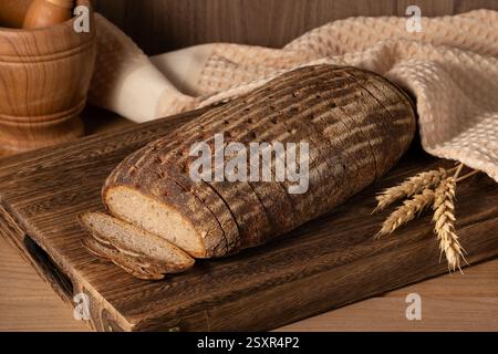 Mehrkörniges Sauerteigbrot mit Leinsamen auf einem Holzbrett, Nahansicht. Gesunde vegane Brotauswahl Stockfoto