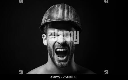 Baumeister Mann, Nahaufnahme Porträt. Bauindustrie. Schreiender wütender Architekt, Vorarbeiter oder Baumeister in Schutzhelm. Schreiender männlicher Ingenieur oder Stockfoto