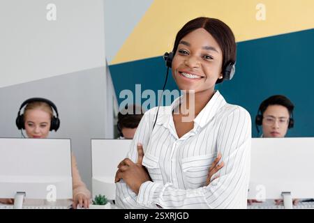 Afroamerikanische weibliche Tech-Support-Betreiber Blick auf Kamera und Lächelnd im Call Center Stockfoto
