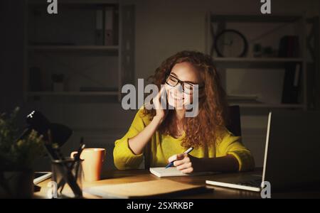 Lächelnde Frau auf der Arbeit, die am Telefon spricht Stockfoto