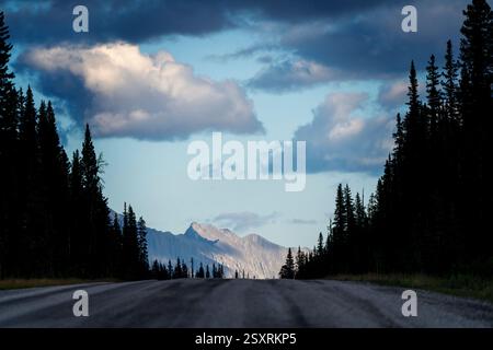 Malerische Aussicht auf eine leere Straße, die unter einem bewölkten Himmel in Richtung Berge führt Stockfoto
