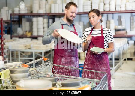 Kollegen in der Keramikwerkstatt diskutieren über eine Reihe von Slipcast-Töpferwaren Stockfoto