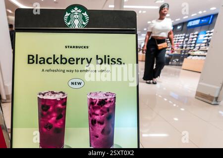 Miami, USA. Februar 2025. Am 25. Februar 2025 läuft eine Frau an Starbucks Signage in einem der Coffee Shops des Unternehmens in Aventura, Florida vorbei. Starbucks hat 1.100 Arbeiter entlassen und schrumpft die Getränkekarte. Foto: Ronen Tivony/SIPA USA) *** Bitte verwenden Sie das Guthaben aus dem Kreditfeld *** Guthaben: SIPA USA/Alamy Live News Stockfoto