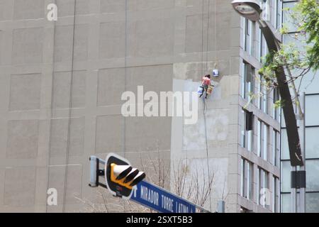 Mexico City, Mexiko; 09 23 2017: Ein Fensterreiniger in der Höhe. Ein Mann, der die Außenfenster eines Gebäudes reinigt. Riskante Jobs. Stockfoto