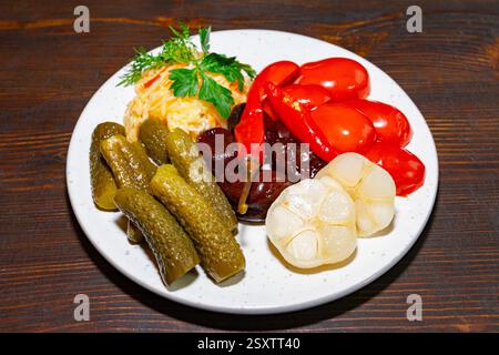 Auf dem lebhaften Teller gibt es eine Auswahl an eingelegtem Gemüse, einschließlich Gurken, Kirschtomaten und Zwiebeln, garniert mit frischen Kräutern. Diese Farbe Stockfoto