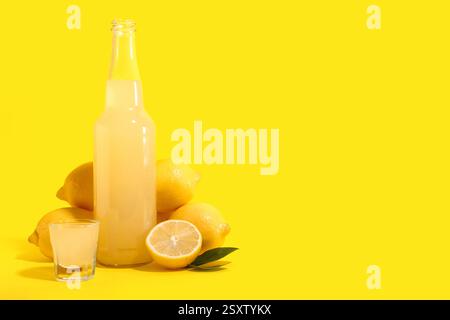 Schuss und Flasche leckeres Limoncello auf gelbem Hintergrund Stockfoto