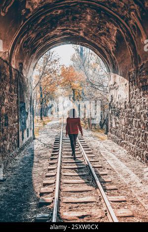 Mädchen im Wald. Das Mädchen läuft mit der Eisenbahn im Wald. Feenwald und Mädchen. Das Mädchen läuft mit der Bahn durch den Tunnel Stockfoto