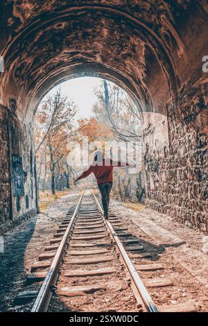 Mädchen im Wald. Das Mädchen läuft mit der Eisenbahn im Wald. Feenwald und Mädchen. Das Mädchen läuft mit der Bahn durch den Tunnel Stockfoto