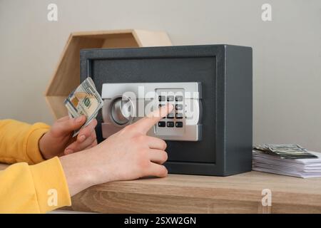 Mann mit Geld, der zu Hause den Safe aufmacht, Nahaufnahme Stockfoto