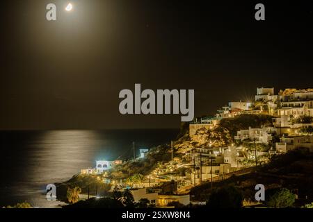 IOS, Griechenland - 5. September 2024 : fantastische Aussicht auf verschiedene beleuchtete Hotels, Restaurants und den Mond über dem Meer am Mylopotas Strand in iOS Griechenland Stockfoto