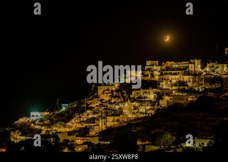 IOS, Griechenland - 5. September 2024 : fantastische Aussicht auf verschiedene beleuchtete Hotels, Restaurants und den Mond über dem Meer am Mylopotas Strand in iOS Griechenland Stockfoto