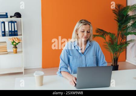 Frau blond, die im Büro online mit Laptop unterrichtet Stockfoto